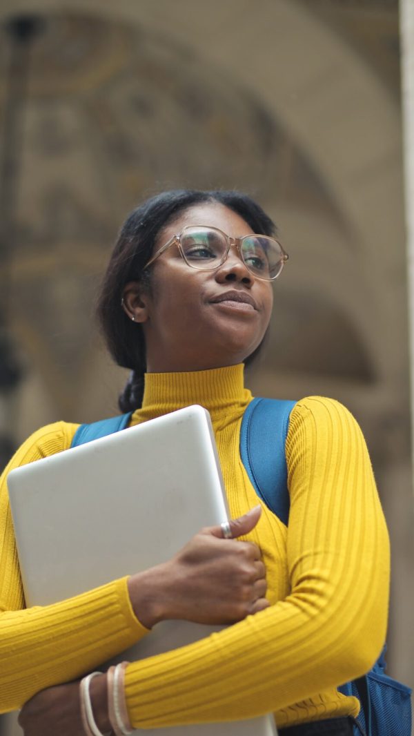 portrait-young-woman-with-laptop-hands-outside-school-min